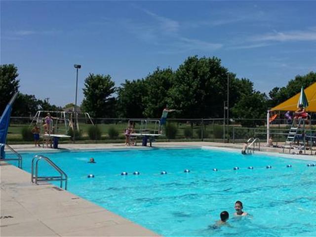 A large swimming pool filled with people swimming and enjoying the water on a sunny day